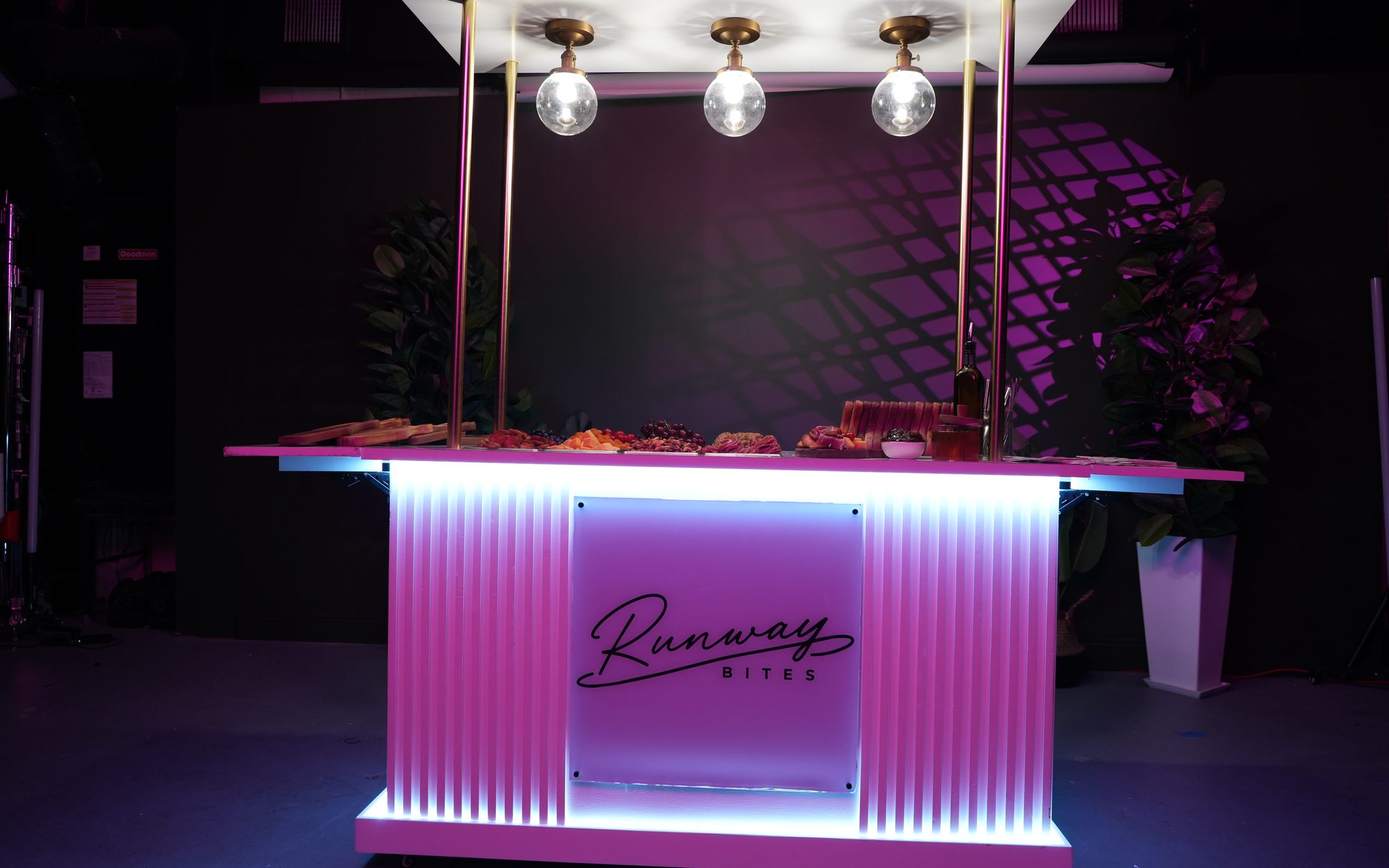The illuminated Runway Bites grazing cart glowing pink and purple at a Miami event